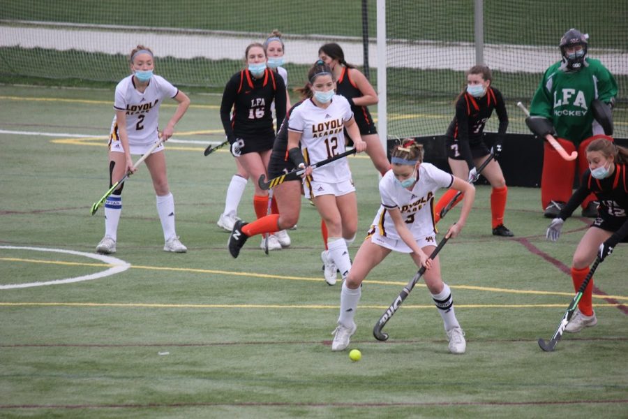 Abby Bevan looks to play the ball near the goal as Ellie Clifford and Caroline Smith look on. Loyola won the Senior Night game 9-1.