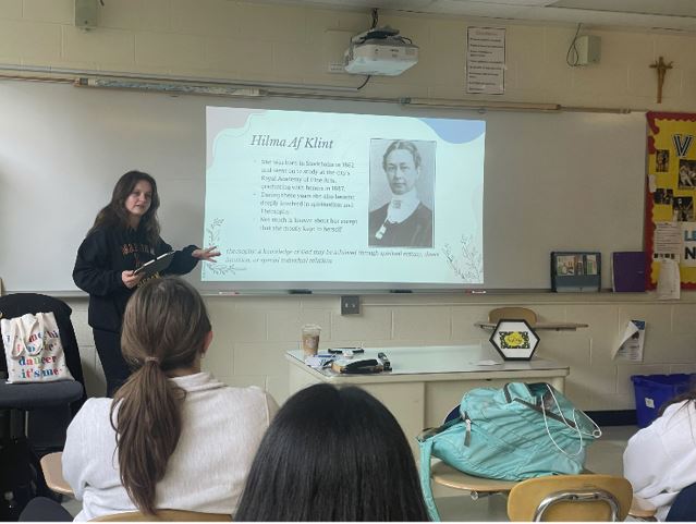 Club co-leader Leah Stein, senior, educates the members on Hilma Af Klint. The group meets every Wednesday after school in Room 11. 